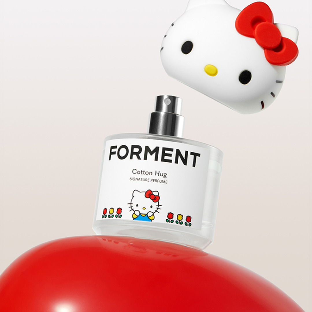 A bottle of Forment Cotton Hug perfume with a Hello Kitty collaboration design is shown with the character-shaped cap lifted above the sprayer, set against a soft gradient background.