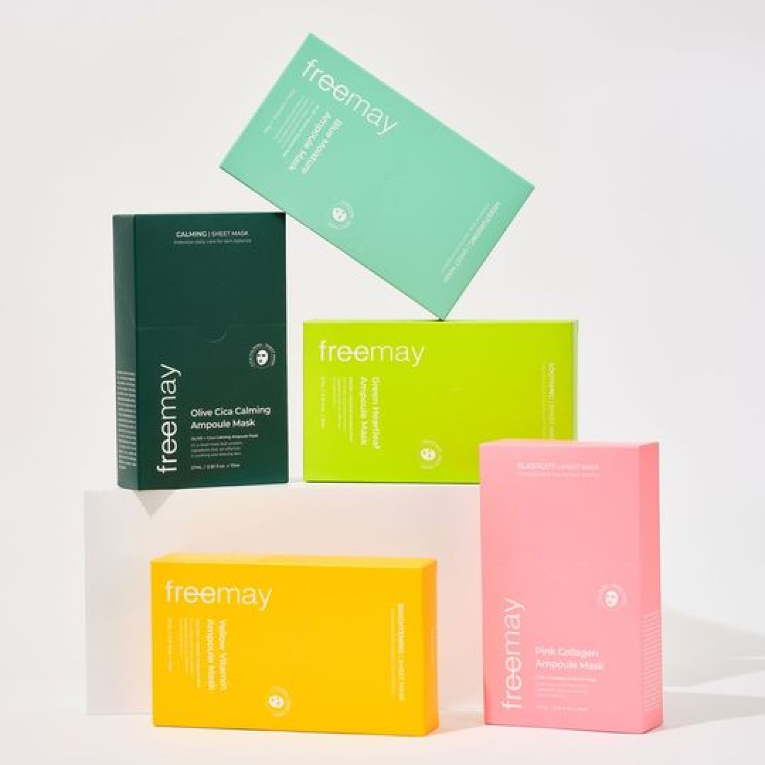 A colorful display of freemay’s ampoule mask packs arranged against a white background. Dark green, mint, lime green, yellow, and pink boxes are stacked and positioned upright, visually representing each product line through its distinct color.