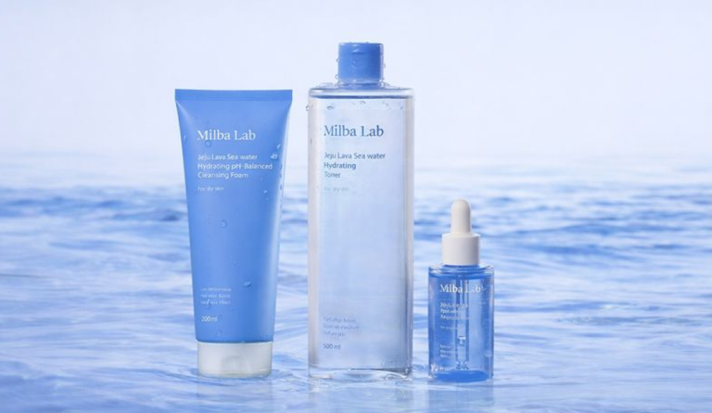 海を思わせる背景に並べられたミルバラボのクレンジングフォーム、トナー、セラムによる韓国の保湿スキンケアルーティン