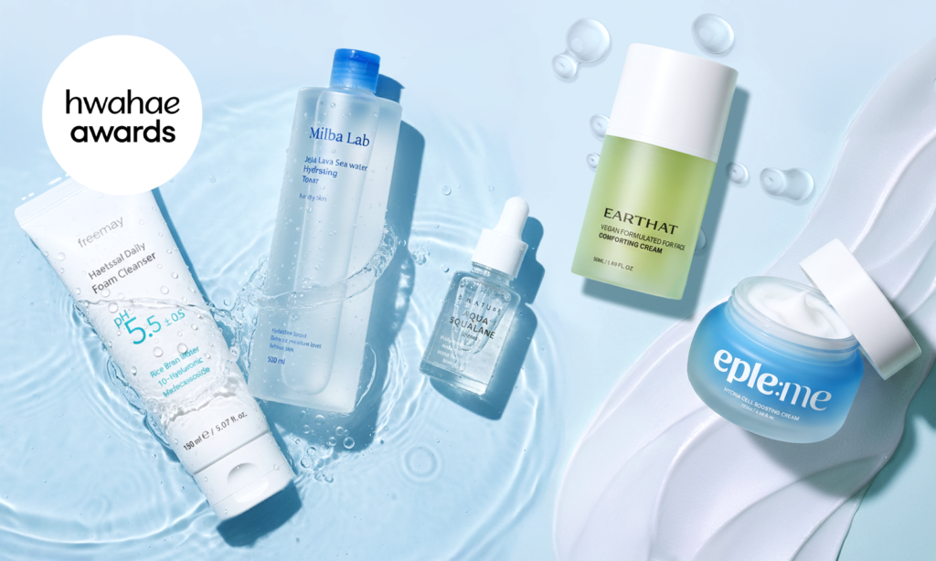 An image of Hwahae Awards–winning hydration skincare products arranged on water. The scene features a mild acidic daily foam cleanser, a Jeju lava seawater hydrating toner, an aqua squalane serum, a vegan comforting face cream, and a hydra cell boosting cream, surrounded by water droplets to highlight Korean hydration skincare and a fresh, dewy routine.