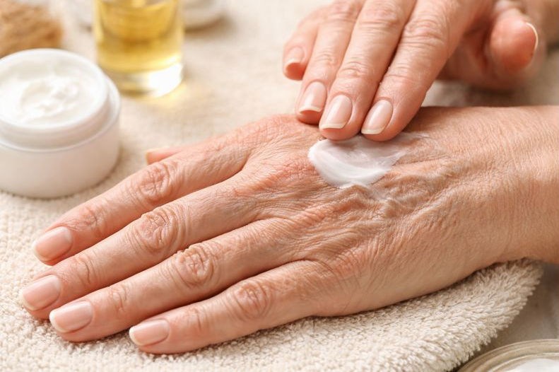 ハンドクリームを塗る際に、ごわつきや小ジワが見られる手元。乾燥やエイジングサインが現れやすい状態を表しており、これらの悩みに特化したハンドケアガイドを紹介するためのキービジュアルです。