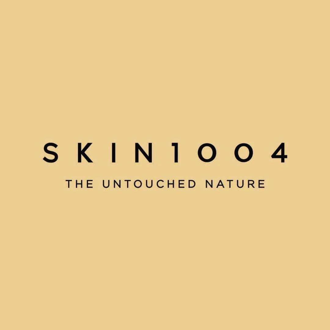 暖かみのあるベージュの背景中央に、黒いサンセリフ体で 「SKIN1004」 と 「THE UNTOUCHED NATURE」 の文字が配置されたミニマルなブランドロゴ画像。