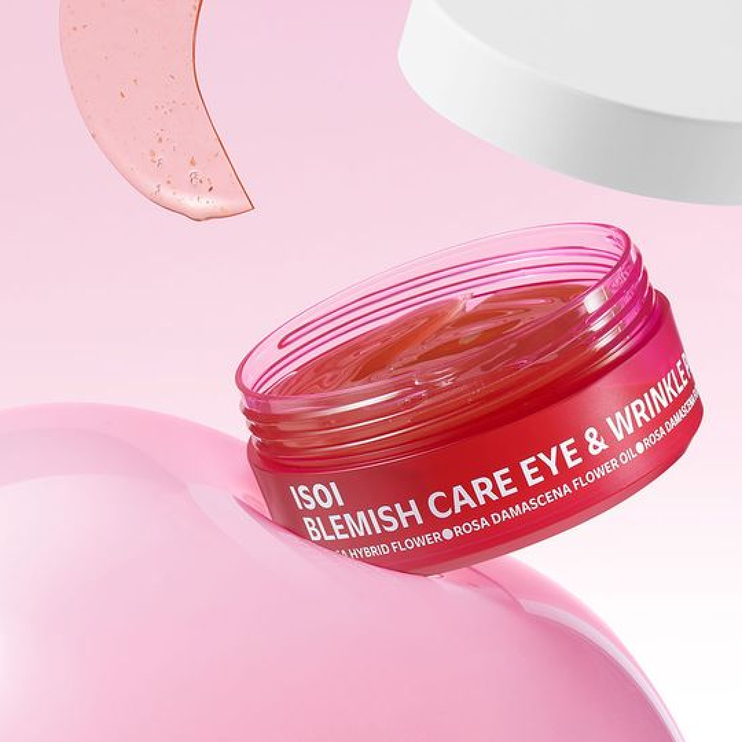 A transparent pink container of ISOI’s Blemish Care Eye & Wrinkle Gel Patch is shown tilted against a pink gradient background. One gel patch is floating above, highlighting the product’s bouncy texture and rose-oil-based soothing care in a bright, modern visual.
