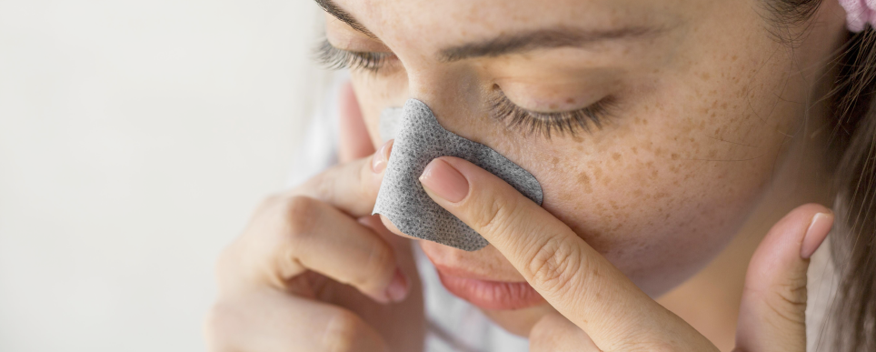 Using a pore strip on the nose for blackhead removal and clogged pores