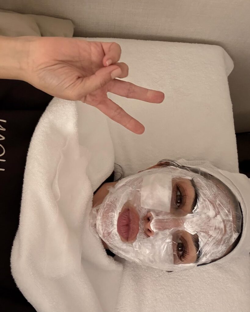kim kardashian skin during a facial treatment in Korea, lying on a clinic bed with a full face mask applied as part of a skin regeneration program