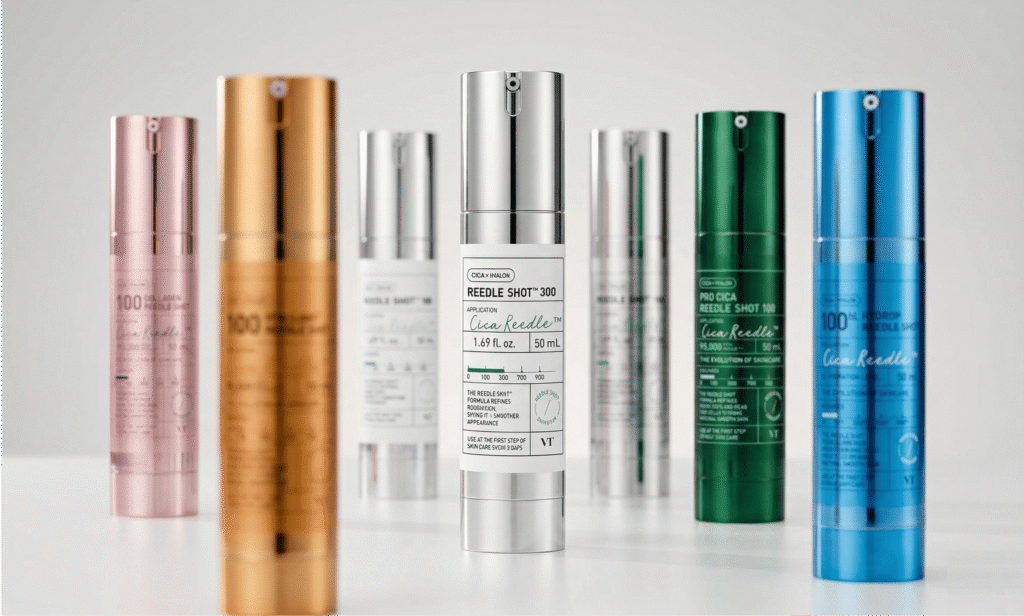 VT Cosmetics Reedle Shot lineup featuring six variants in different colored bottles — including Collagen Reedle Shot 100 in pink, Reedle Shot 100 in gold, Reedle Shot 300 in silver, Pro Cica Reedle Shot 100 in green, and Hydrop Reedle Shot 100 in blue — arranged on a neutral surface with the Reedle Shot 300 front and center.