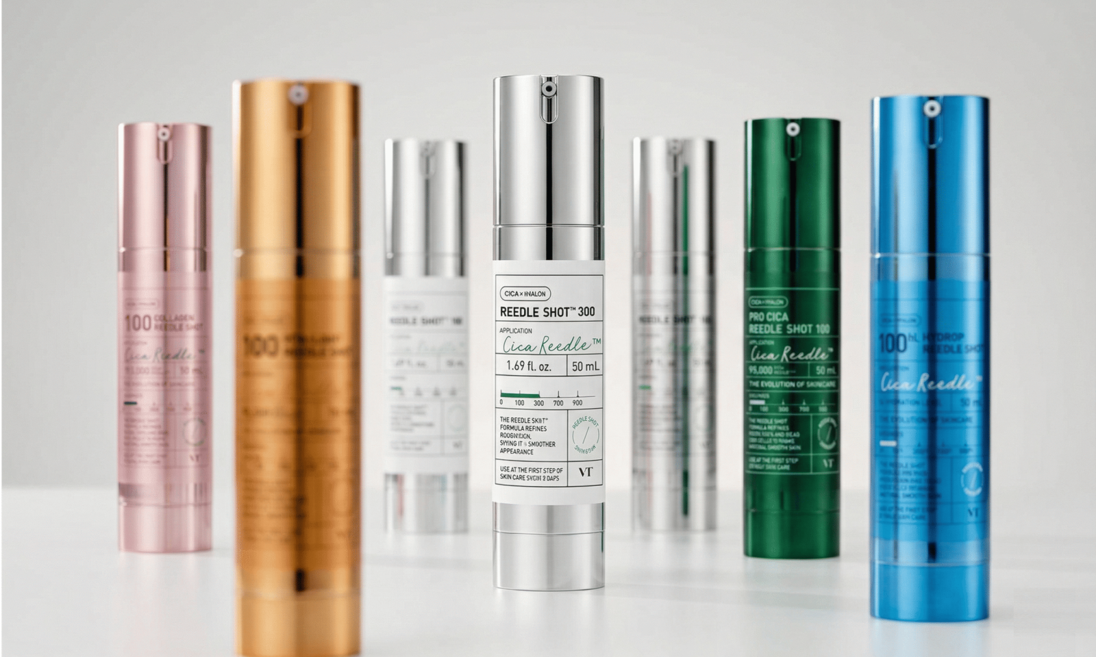 VT Cosmetics Reedle Shot lineup featuring six variants in different colored bottles — including Collagen Reedle Shot 100 in pink, Reedle Shot 100 in gold, Reedle Shot 300 in silver, Pro Cica Reedle Shot 100 in green, and Hydrop Reedle Shot 100 in blue — arranged on a neutral surface with the Reedle Shot 300 front and center.