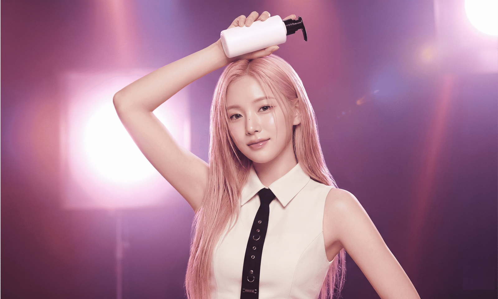 K-pop idol with pink hair applying hair care product on stage-style lighting background, illustrating a K-pop idol hair care routine.